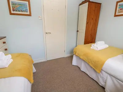 a bedroom with two beds with towels on them at Bumbles in Padstow