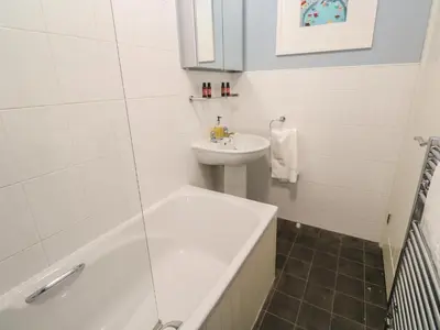 a white bathroom with a sink and a tub and a toilet at Bumbles in Padstow
