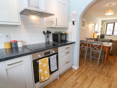 a kitchen with white cabinets and a stove top oven at Bumbles in Padstow