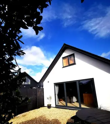 a white house with a large window in a yard at Gwynn Lodge in Newquay