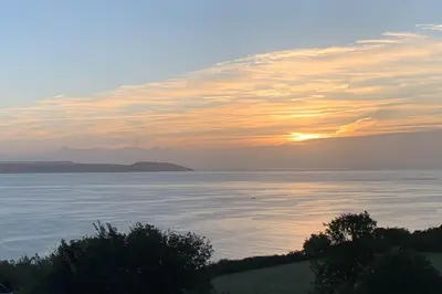 a sunset over a body of water with trees at The Post House in Charlestown