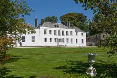 a large white house with a green lawn at Trewardale in Bodmin