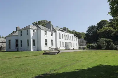 a large white house with a large grass field at Trewardale in Bodmin