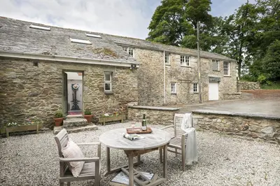 a table and chairs in front of a stone house at Trewardale in Bodmin