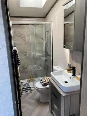 a bathroom with a shower and a toilet and a sink at Bailey Lodge in Padstow