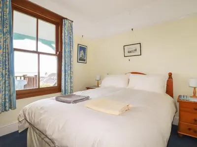 a bedroom with a large white bed with a window at Beachcliff in Gorran Haven