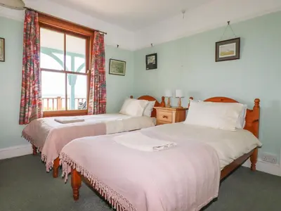 two beds in a room with a window at Beachcliff in Gorran Haven