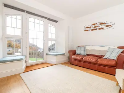 a living room with a brown leather couch and windows at Cliffside in Tintagel