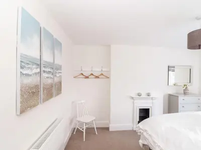 a white bedroom with a bed and a chair at Cliffside in Tintagel