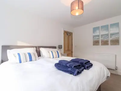 a bedroom with a white bed with blue towels on it at Cliffside in Tintagel