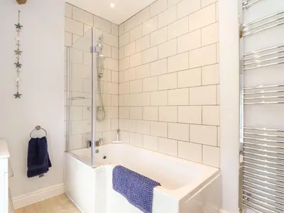 a white bathroom with a tub and a shower at Cliffside in Tintagel