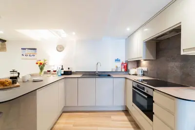 a kitchen with white cabinets and a sink at The Boathouse in St Ives