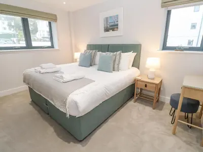 a bedroom with a large bed and two windows at Sebastian's View in Falmouth
