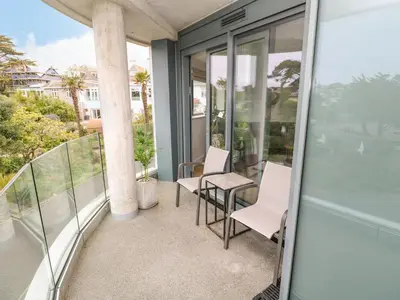 a balcony with white chairs and glass walls at Sebastian's View in Falmouth