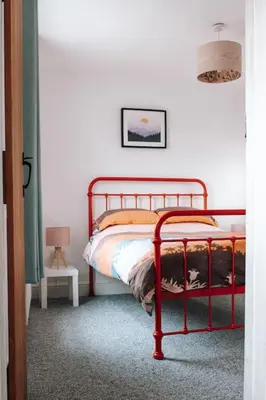 a bedroom with a red metal bed in a room at Albion Cottage central Falmouth with parking and 10 minutes to the beach in Falmouth
