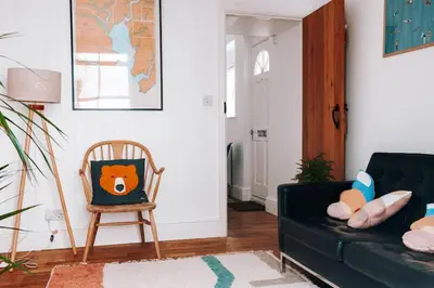 a living room with a black couch and a chair at Albion Cottage central Falmouth with parking and 10 minutes to the beach in Falmouth