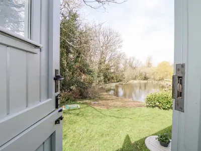 a door to a yard with a view of a river at Gwithian Shepherds Hut in Hayle